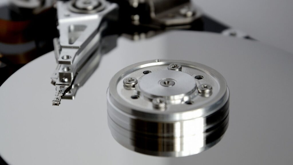 Close-up of an open hard disk drive platter and read arm, representing cryptography stored at rest in code and on file shares