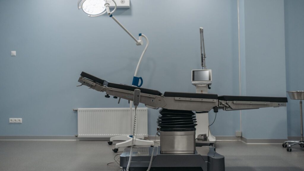 Empty modern operating room with a surgical table, overhead light and connected medical equipment